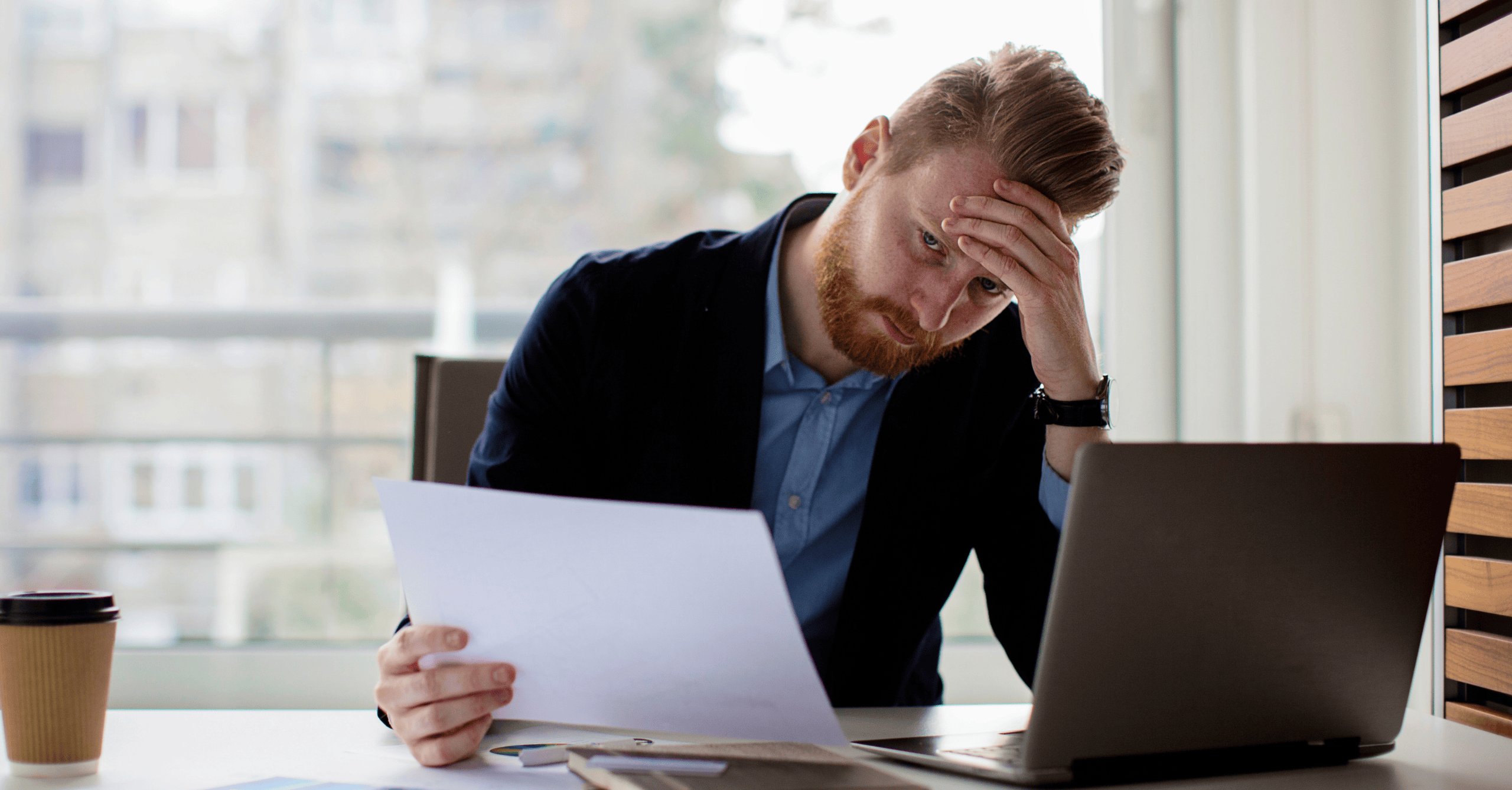 Professional man in a blue suit looking thoughtful, with a busy team in the background and text bubbles highlighting business challenges like too many meetings and inefficiency. GirlFriday Business Solutions helps businesses overcome these obstacles with expert solutions