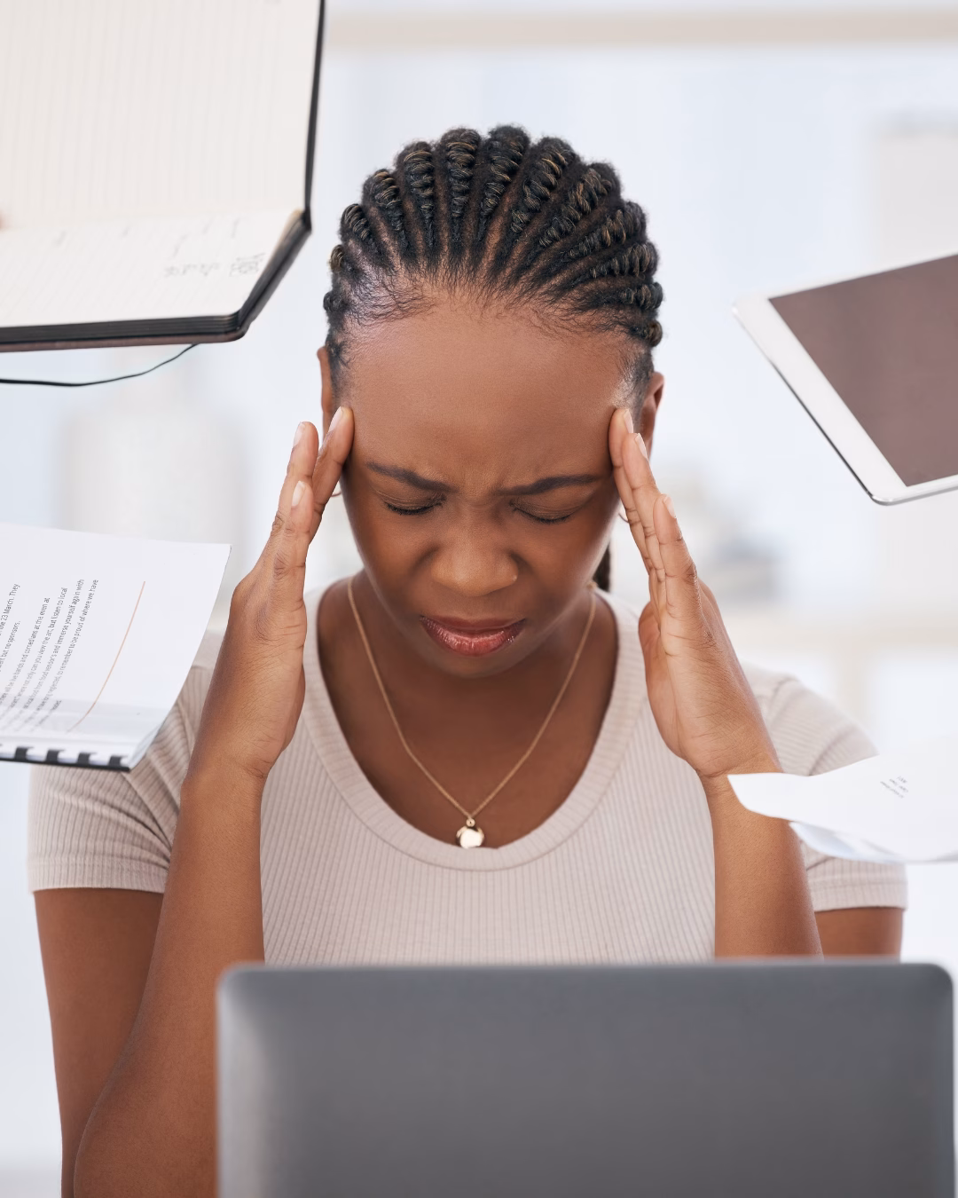 Stressed businesswoman sitting at desk with financial reports, appearing overwhelmed by work or decision-making